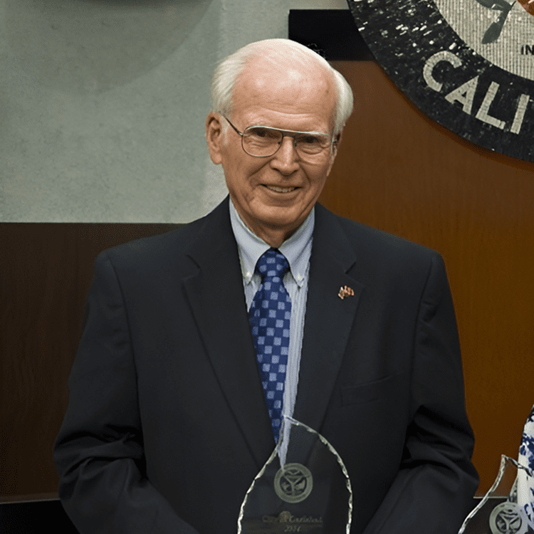 Frank-about Elderly man in suit holding an award.