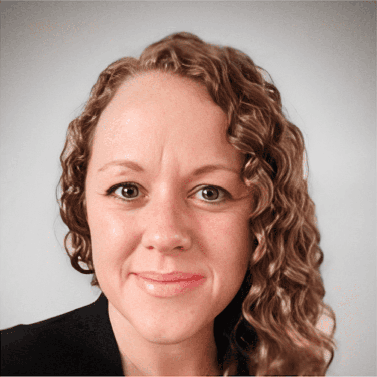 about-1 Curly-haired person smiling against plain background.
