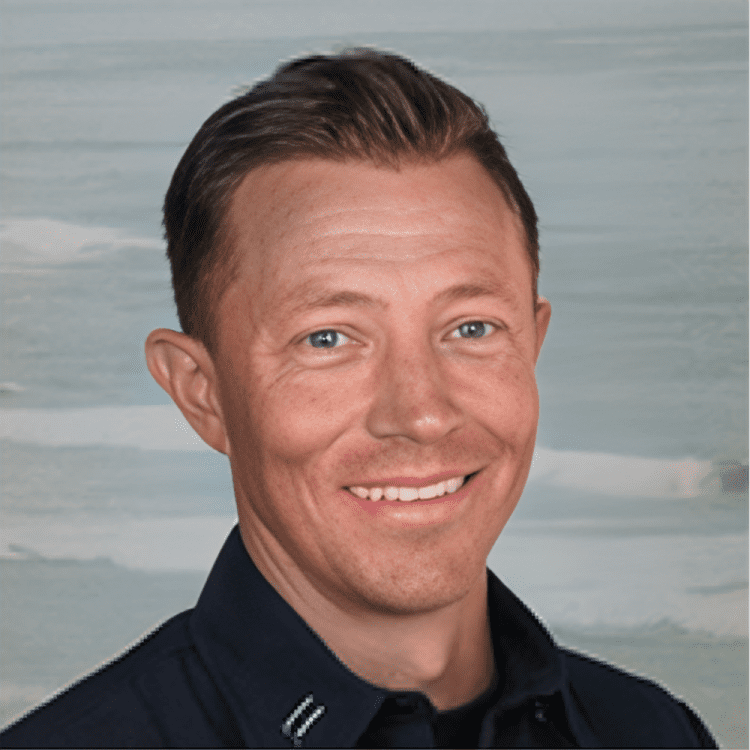about-6 Smiling man in dark shirt, neutral background.