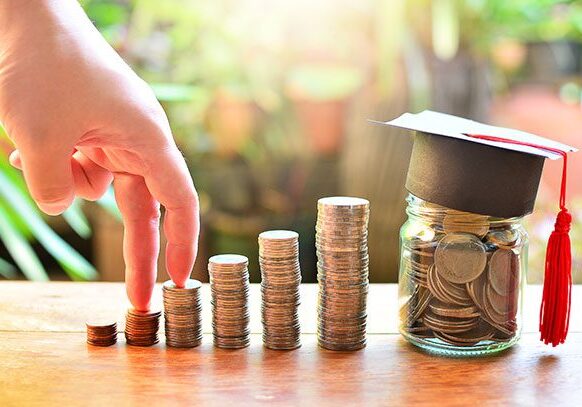 cfdf-scholarships Stacks of coins and jar with graduation cap.