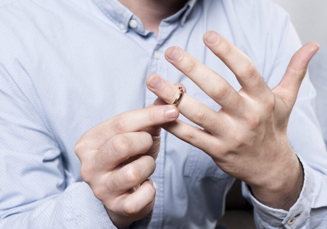 close-up-man-taking-wedding-ring-off-finger Man removing a wedding ring from finger.