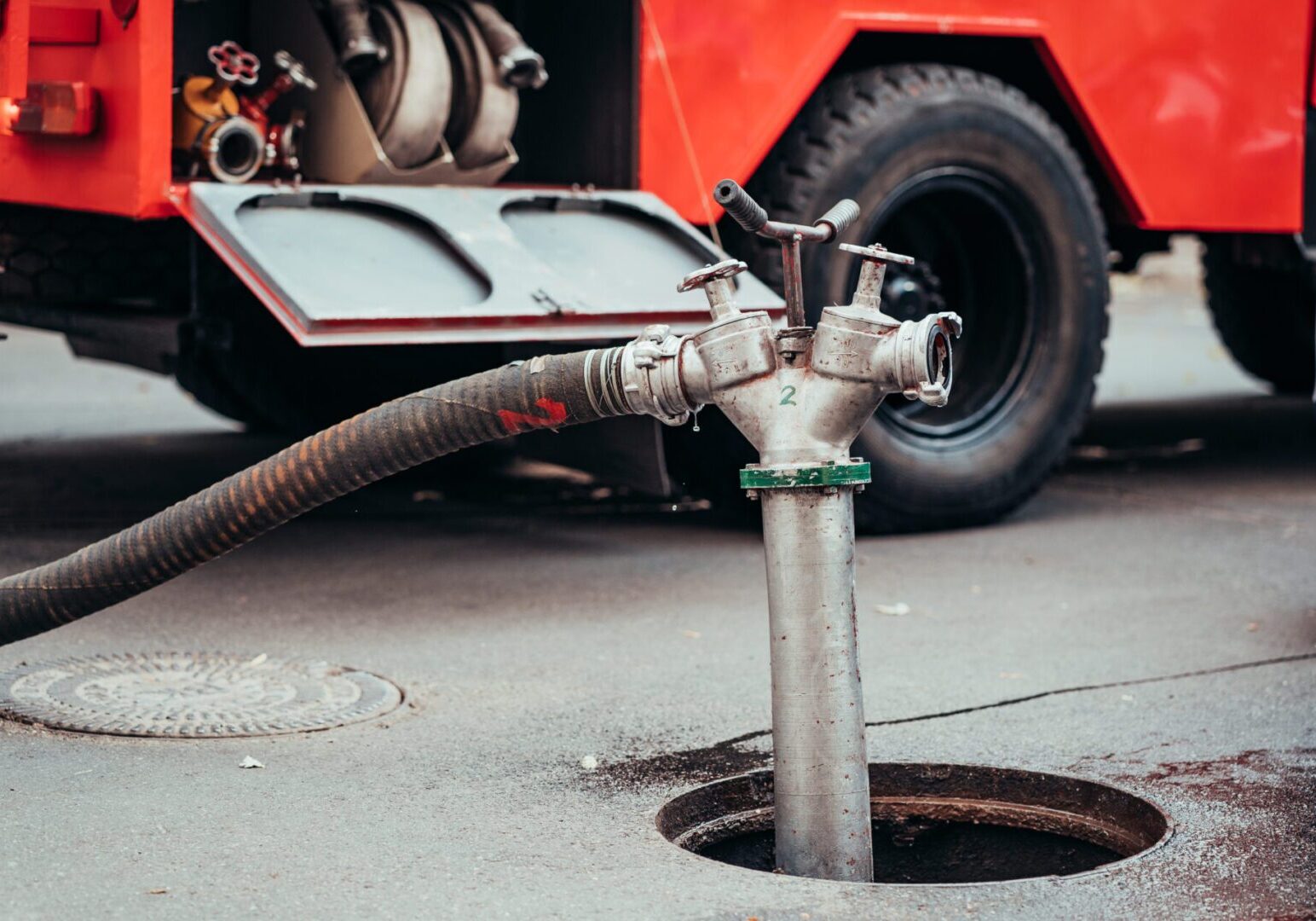 Fire Hydrant In Use During a Structure Fire Fire truck hose connected to hydrant valve.